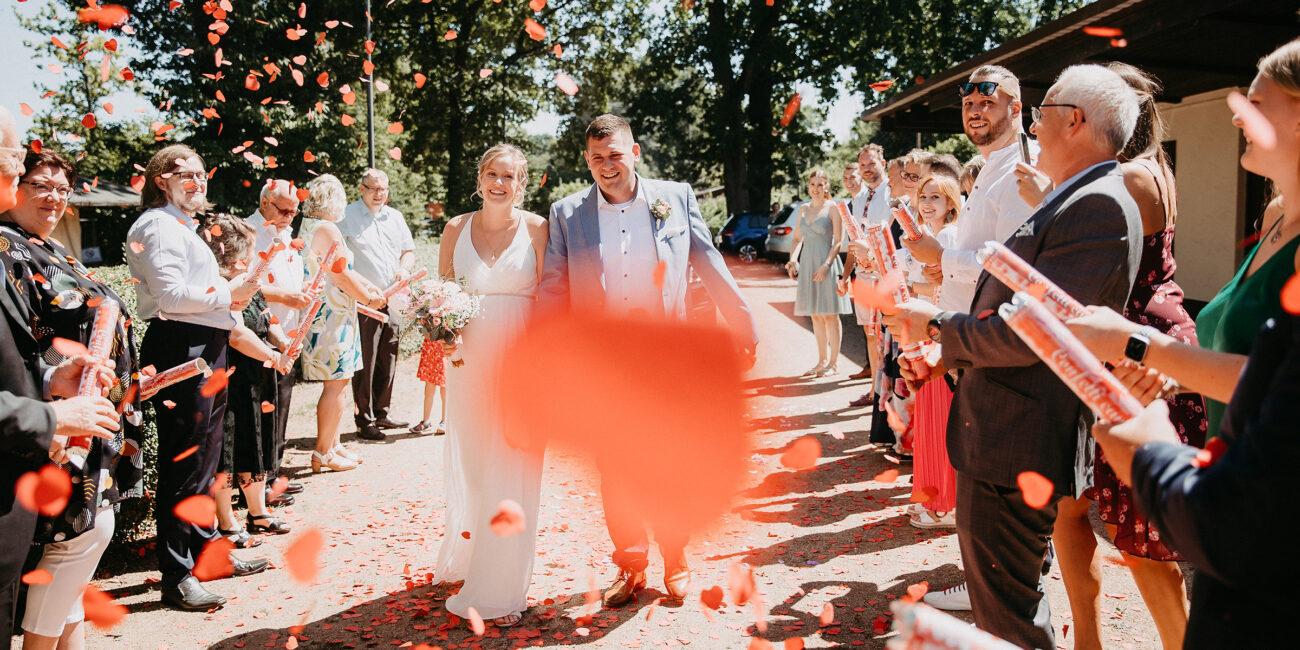 Braut und Bräutigam lauden durch Blüten und Konfetti an der Ehemalige Synagoge in Großkrotzenburg.